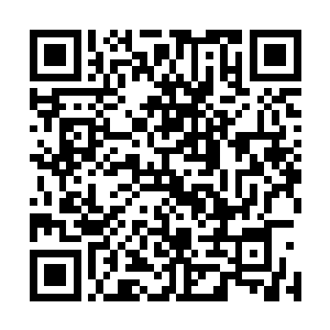 在他身前办公桌上放着一个较为帅气的男子照片和一些资料二维码生成